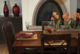 A table with two chairs and a vase of flowers.